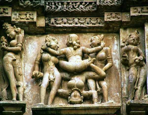 on the southern wall, shows a woman facing the viewer, standing on her head, engaged in intercourse, although her partner is facing away from the viewer and their gender cannot be determined. She is held by two female attendants on either side and reaches out to touch one of them in her pubic area.